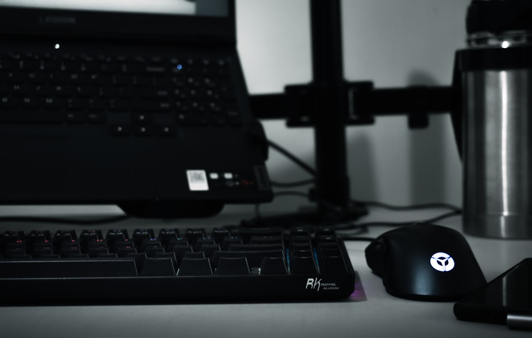 a computer keyboard, mouse, and a laptop on a desk