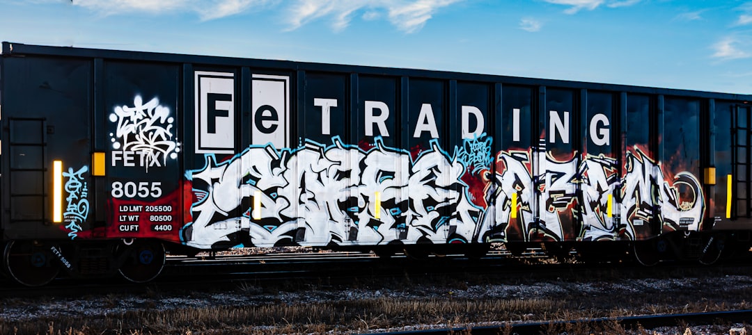 Black train car with graffiti and "fe trading" text.